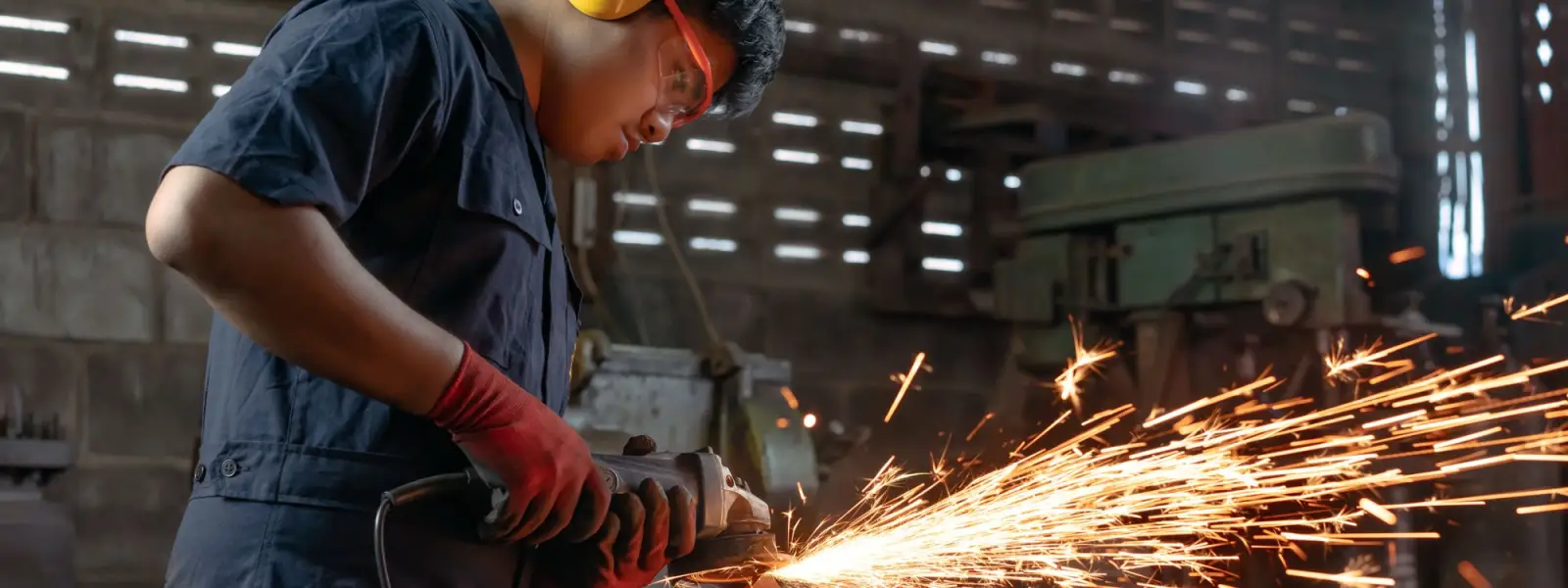An engineer grinding metal in a workshop, sending out a shower of sparks
