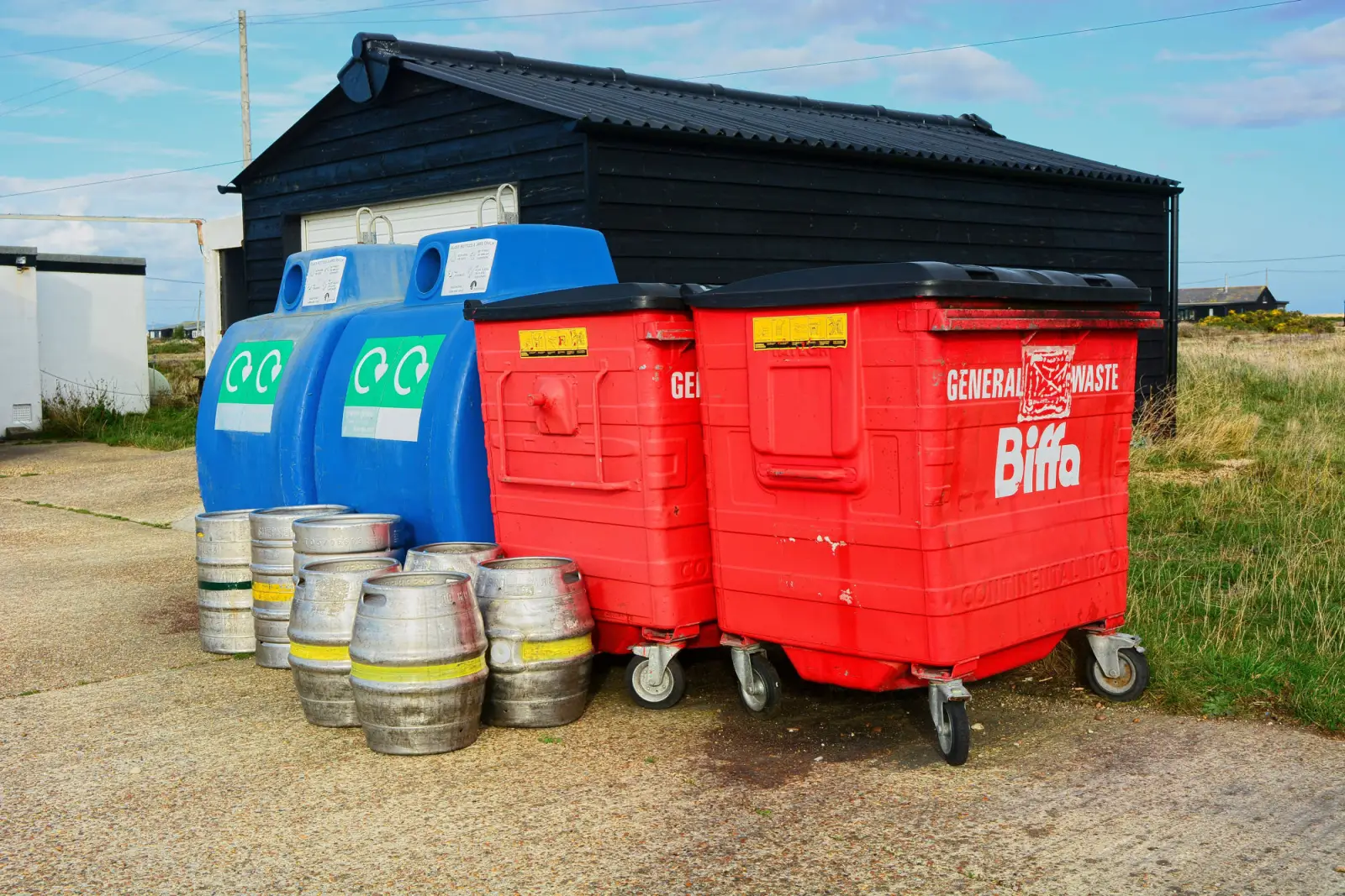 Commercial waste and recycling bins with beer kegs outside a business premises